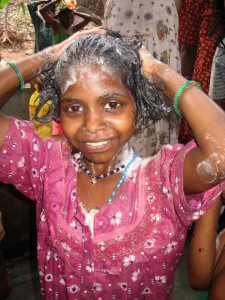 A young girl shampoos her hair with medicated shampoo in Tamil Nadu, India.