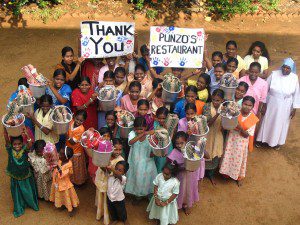 Children at Sirumalar Orphanage in Tamil Nadu, India hold up thank you signs for Punzo's restaurant.