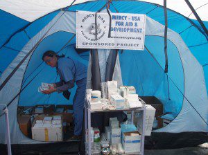 CMAT Paramedic retrieves Elizabeth Grant supplies from a tent funded by Mercy USA.