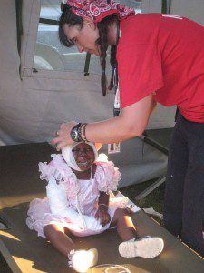 NP Sandra Hodge dresses a little girl's head wound in Leogane, Haiti