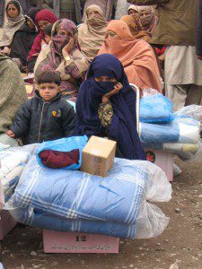 Women sit with relief supplies distributed to them by CMAT staff