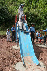 Young school girls enjoy playing on their new playground equipment.