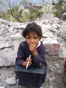 A little girl sits thoughtfully with her slate. Kashmiri children are resilient and are eager to study and learn. 