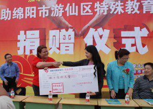 CMAT Executive Director Valerie Rzepka shakes hands and provides a donation of ¥85,000 RMB to Ms. Ma, Chairperson of Mianyang Municipal Handicapped Federation