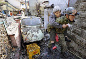 A stranded elderly woman is carried on the back of a Japanese soldier after being rescued from a residence at Kesennuma, northeastern Japan. (Photo Courtesy Kyodo News/AP)