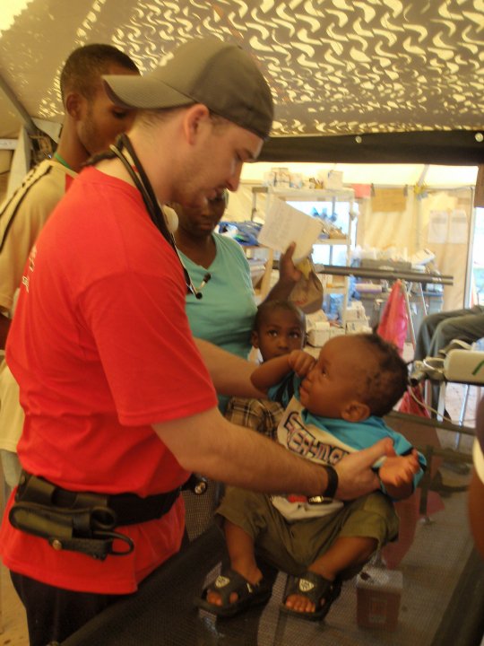 Brandon Duncan, RN assesses a small child in CMAT's field clinic in Pétionville, Haiti. April 2010. 